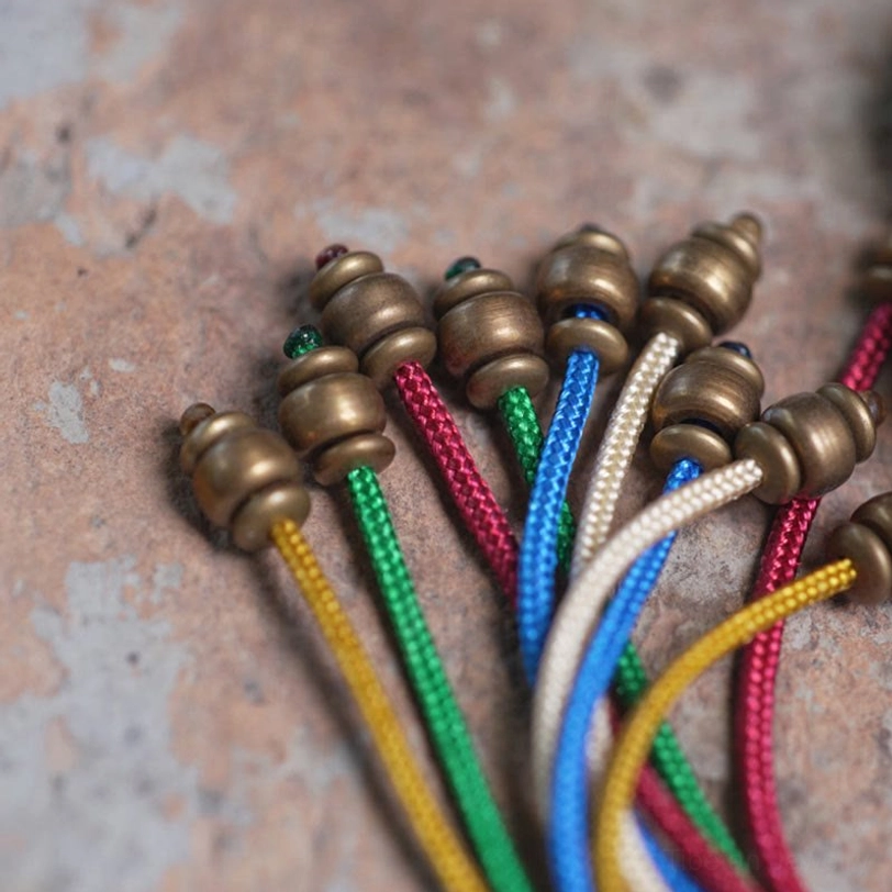 Colorful silk peace tassel with brass metal end caps close-up flat lay