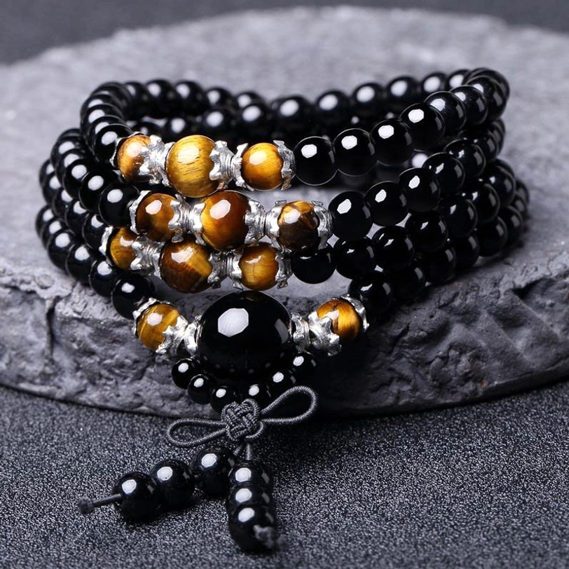 Multi-strand tibetan mala set with obsidian and tiger eye beads, flat lay on dark stone countertop