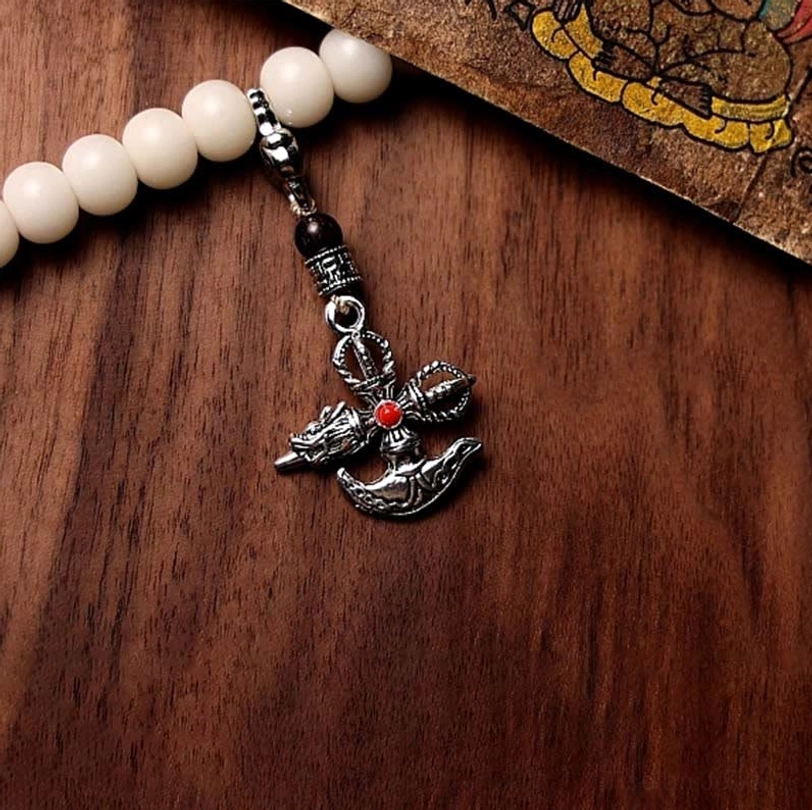 Mala bracelet with silver vajra pendant inlaid red gem detail and white bodhi beads on Buddhist pattern card