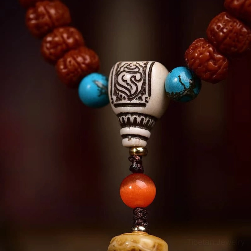 Mala guru bead section side close-up showing silver carved guru bead, turquoise spacers, and reddish agate bead