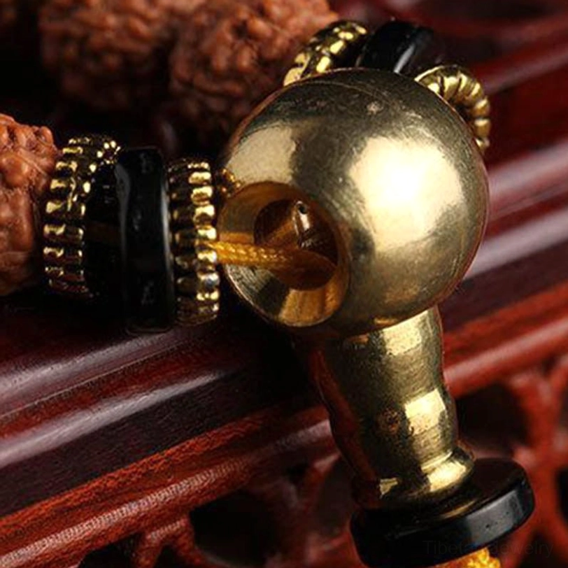 Guru bead component of meditation mala with large golden brass bead, black spacers, and decorative metal wrapping