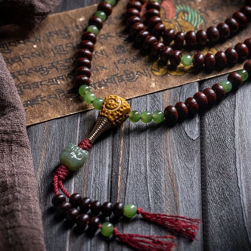 Tibetan mala section showing red tassel, metal end cap, and alternating purple and jade beads