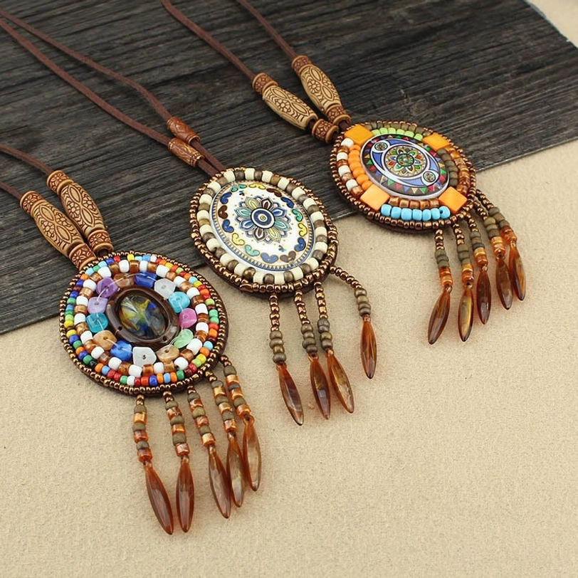 Multiple colorful beaded mandala pendants with leather tassels and wax cord necklaces arranged in bohemian style layout