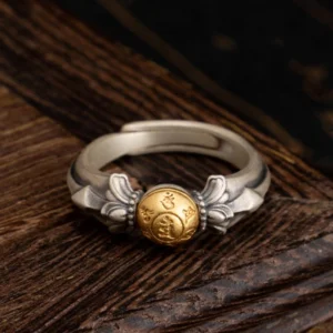 925 sterling silver Manjusri Om Mani Padme Hum adjustable ring with matte finish and gold mantra bead, front view on wooden surface