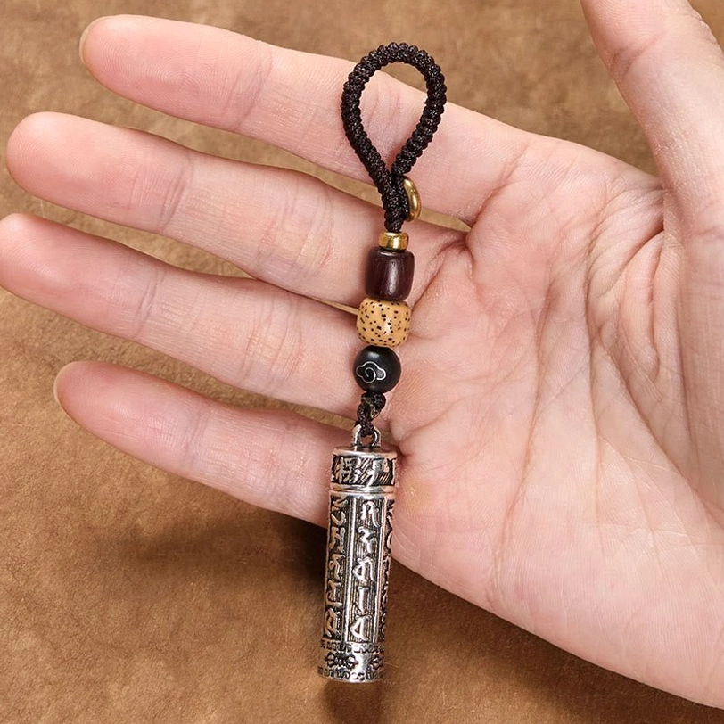Om Mani Padme Hum keychain held in hand showing size scale, engraved copper pendant with mixed beaded lanyard