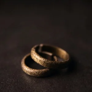 Pair of matching Tibetan vintage copper couple rings stacked together - overhead angled view showing textured bronze surface and complementary design