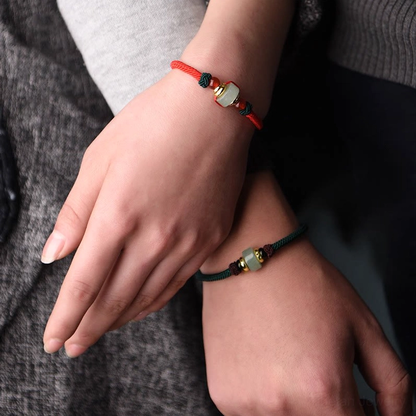 Couple matching Tibetan red and dark green braided luck bracelets on wrists showing how to wear together