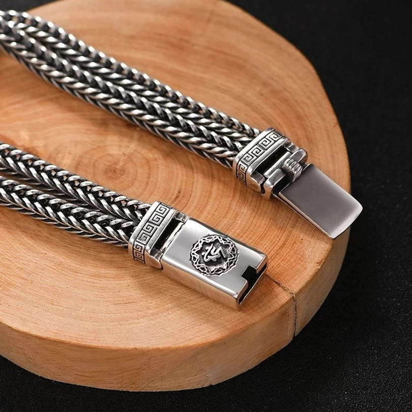 Pair of matching Om Mani Padme Hum braided bracelets with Buddhist symbols engraved on buckles, displayed together on black background