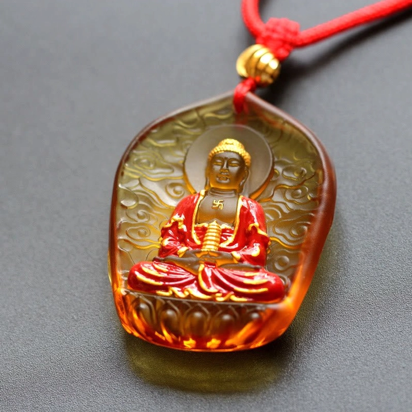 Tibetan Medicine Buddha pendant with auspicious clouds Liuli design, carved cloud pattern, purple-blue glass, gold halo, red robed Buddha, and black braided cord