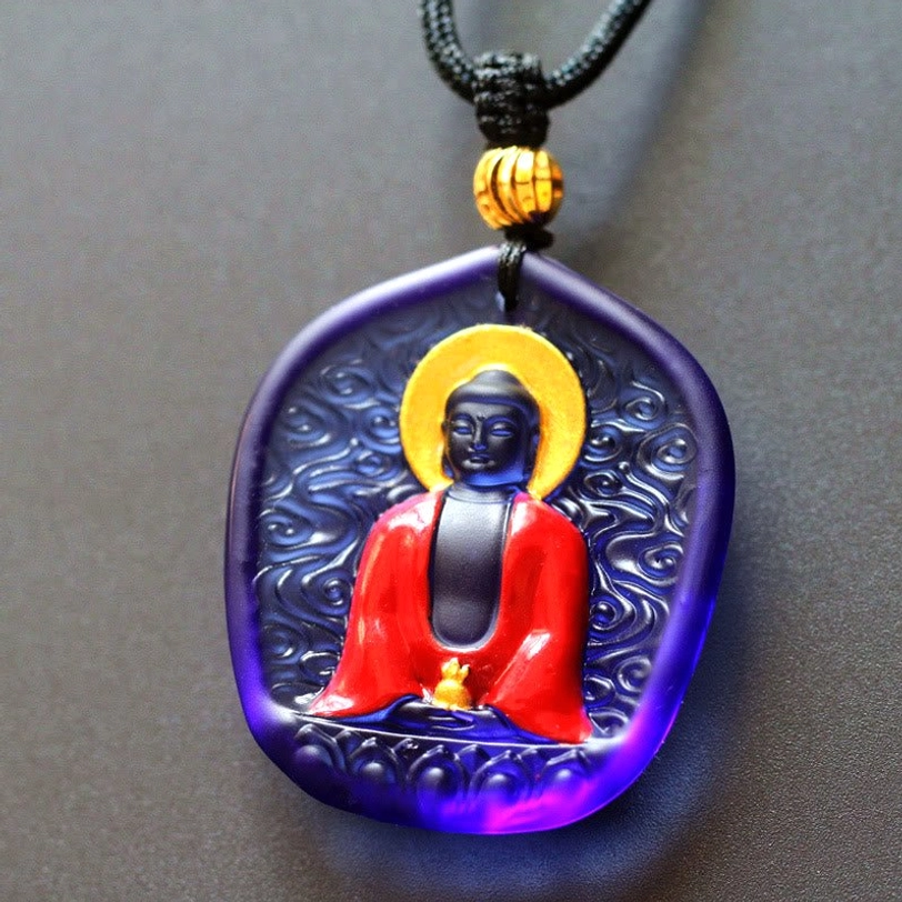 Classic Medicine Buddha Liuli crystal pendant featuring traditional Buddha design with gold leaf halo, ritual vessel, lotus base, dark blue glass frame, and silk cord