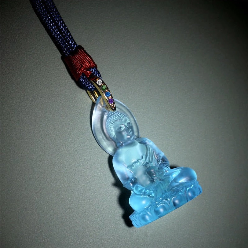 Medicine Buddha crystal pendant low-angle view on gray gradient background, showcasing matte light blue Liuli texture and colored gem metal bail