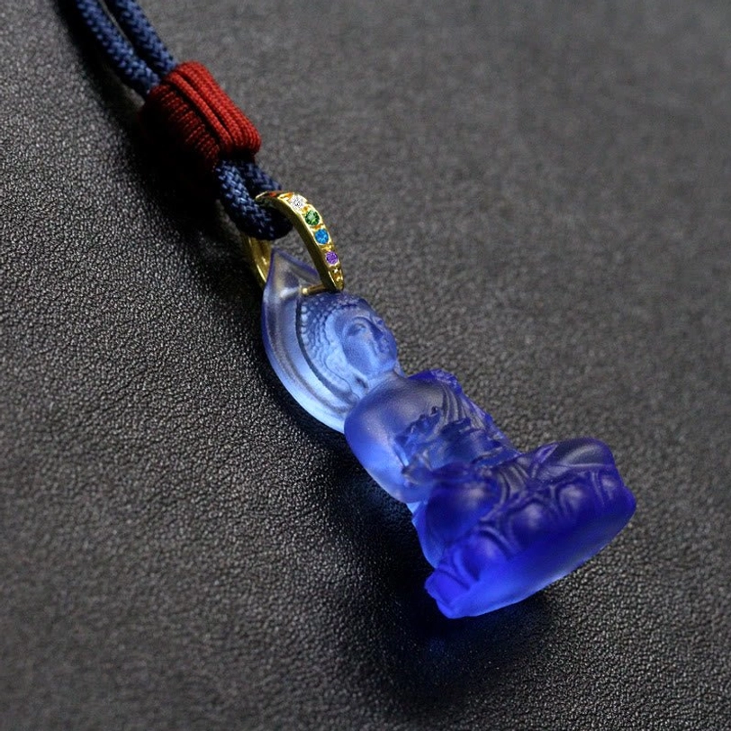 Medicine Buddha Liuli crystal pendant single piece display, light blue translucent stone showing detailed Buddhist deity carving and setting