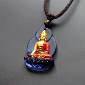 Compact Medicine Buddha Liuli crystal pendant necklace with blue base, brown braided cord, and blue accent bead, flat lay view
