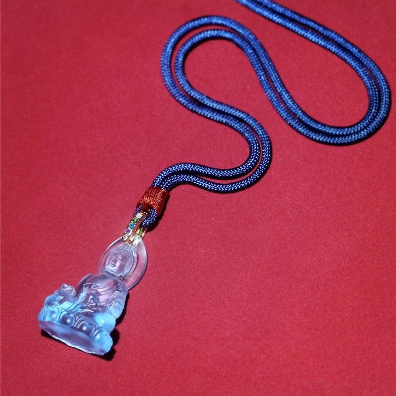 Complete Medicine Buddha necklace laid flat on red background, showing full-length dark blue woven cord with assembled pendant set