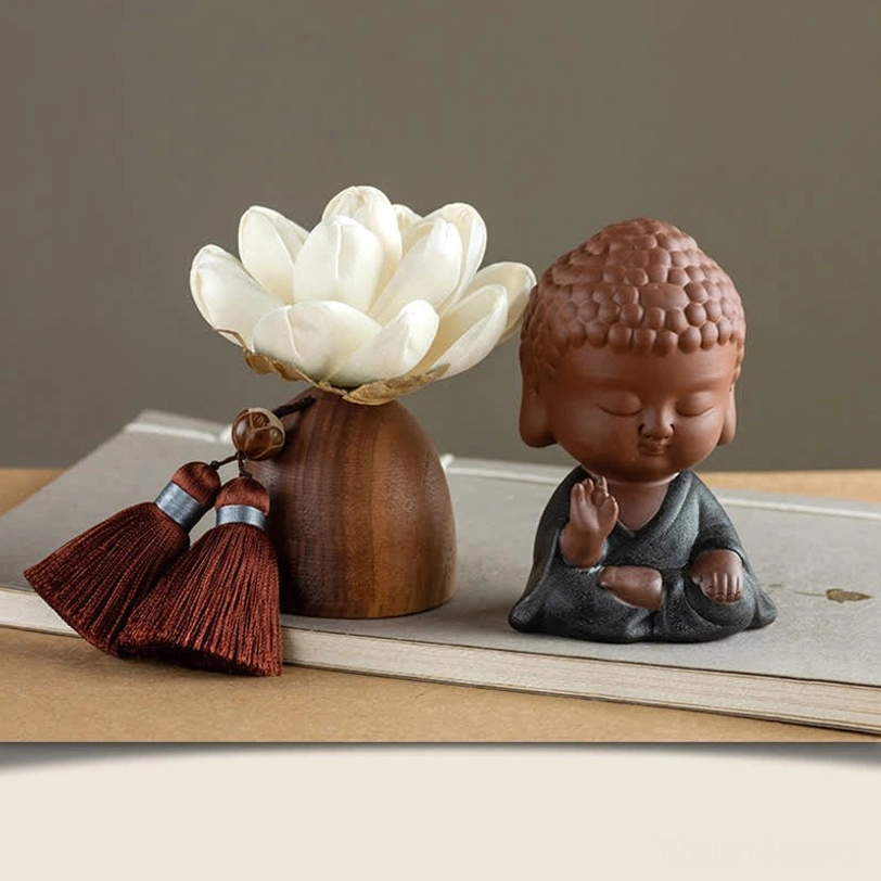 Buddha figurine in grey robe with lotus holder and tassel accents on wooden base, desk display