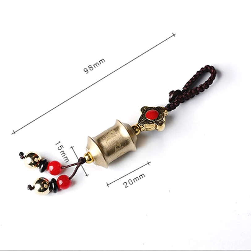Mini Prayer Wheel brass keychain with compact cylinder design and red bead tassels, size scale reference showing portable charm