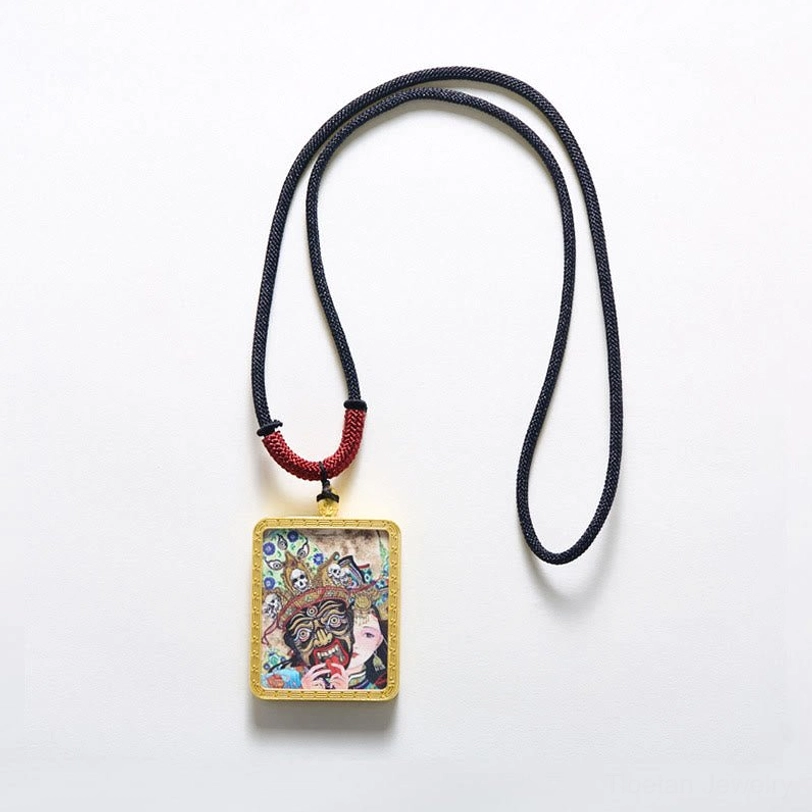 Minimalist Tibetan thangka pendant necklace with small gold frame on pure white background and black-red woven cord