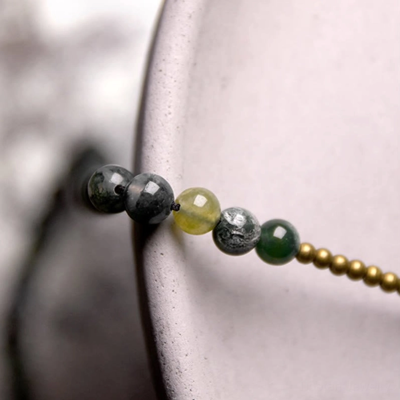 Close-up macro detail of moss agate stone beads with copper spherical spacer beads showing texture and natural green coloring