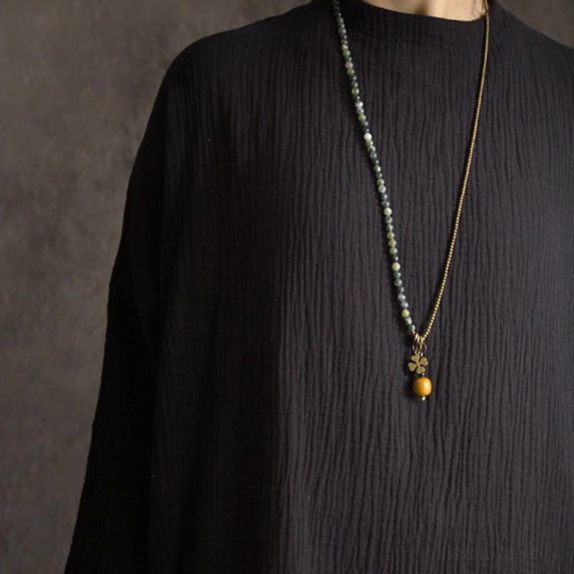 Long moss agate and copper beaded necklace with brass clover pendant and orange bead on mannequin torso display