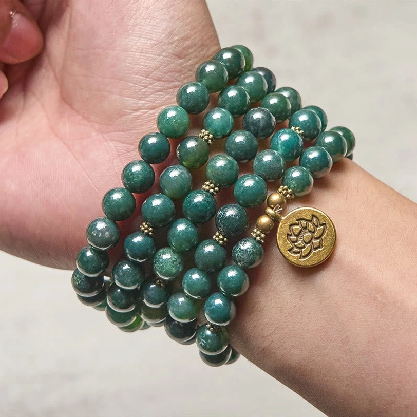Moss agate mala bracelet worn on wrist showing wrapped beads and golden lotus charm in daily wear styling