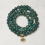 Moss Agate 108-bead Tibetan mala bracelet with golden lotus charm, flat lay view showing polished green agate beads and brass spacers