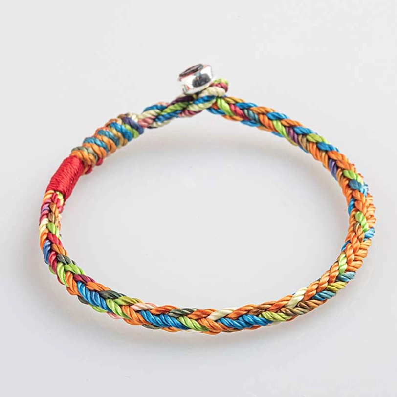 Colorful woven friendship bracelet circular loop design overhead view showing red cord at clasp closure