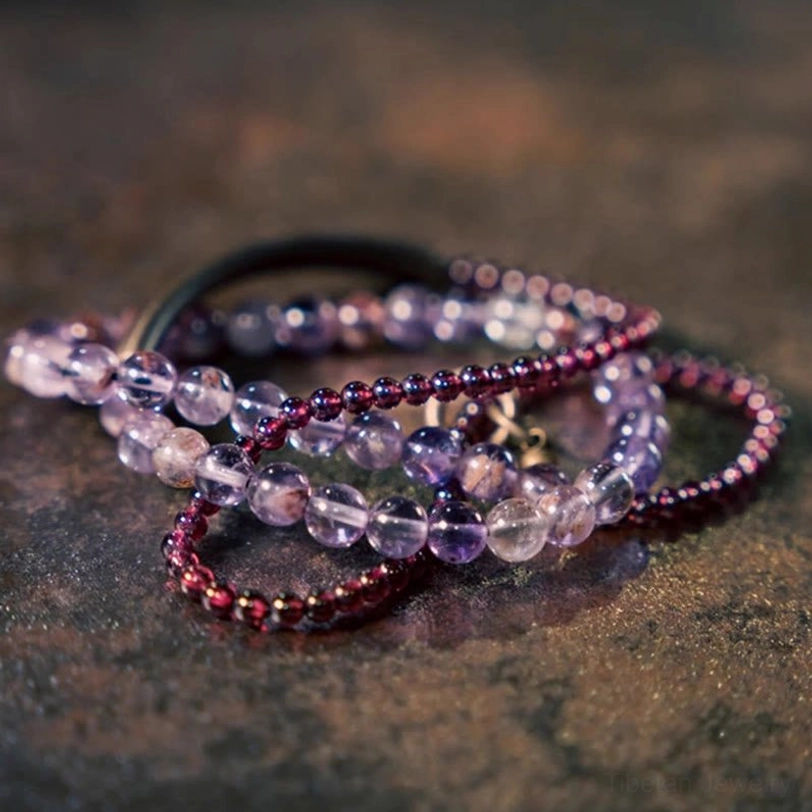 Stacked gemstone bracelets overhead view with mixed amethyst and garnet beads on rustic surface
