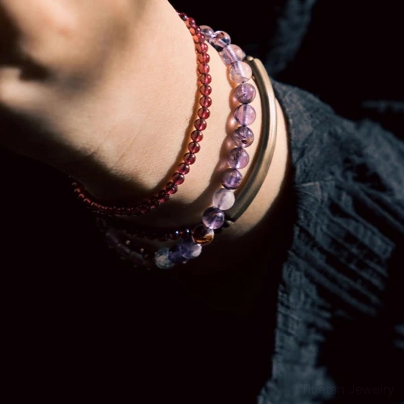 Spiritual balance bracelet with amethyst and garnet beads arranged on natural stone surface