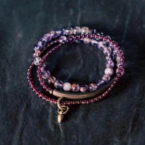 Multi-layer amethyst garnet crystal bracelet flat lay with purple and red beads and metal hardware