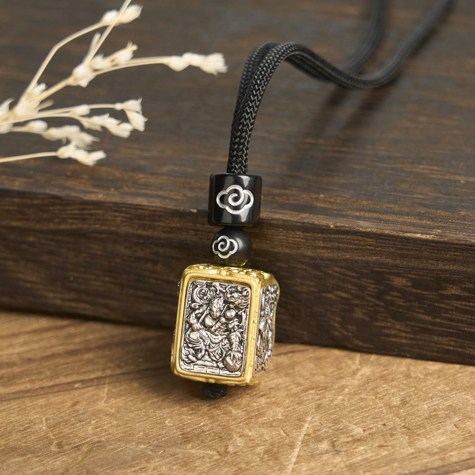 Mythical Beast guardian tibetan pendant necklace close-up, showing silver intricate deity carving with gold frame finish and cloud-patterned black spacer beads