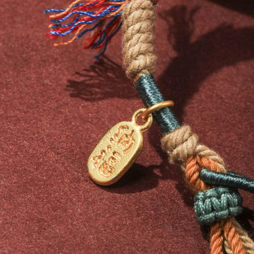 Close-up macro view of braided Tibetan rope texture with Chinese Fu character gold charm and knotted details