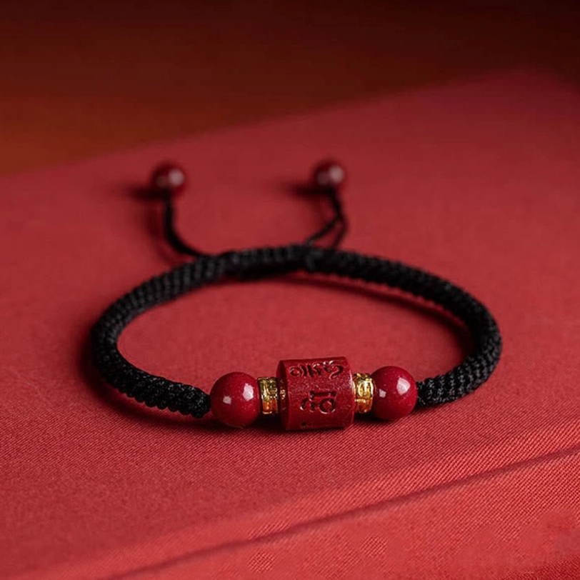 Natural cinnabar beads and Om Mani Padme Hum engraved bead in handwoven Tibetan blessing bracelet - material close-up