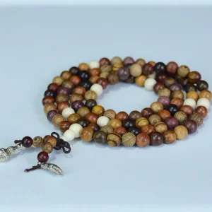 Multi-tone natural wood Tibetan prayer mala flat lay on light blue background showing warm-toned wooden beads
