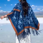 Navy paisley Tibetan shawl with tassel fringe, white geometric patterns on dark blue base, shown in back three-quarter view at alpine salt lake landscape