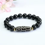 Nine-eye dzi bead black onyx bracelet displayed overhead with nine-eye dzi focal bead and polished black onyx beads with gold spacers
