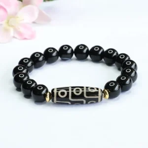 Nine-eye dzi bead black onyx bracelet displayed overhead with nine-eye dzi focal bead and polished black onyx beads with gold spacers