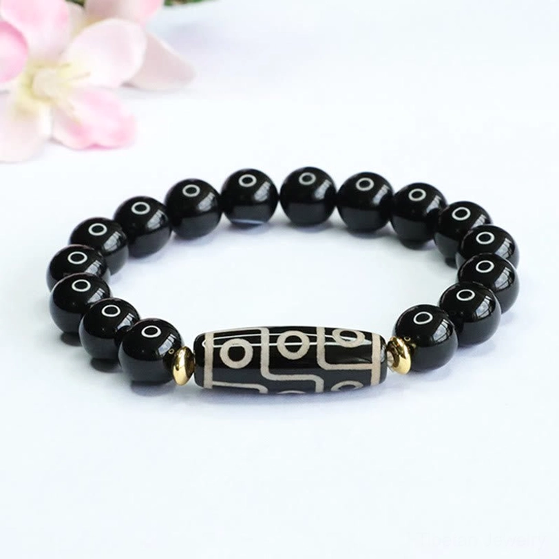 Nine-eye dzi bead black onyx bracelet displayed overhead with nine-eye dzi focal bead and polished black onyx beads with gold spacers