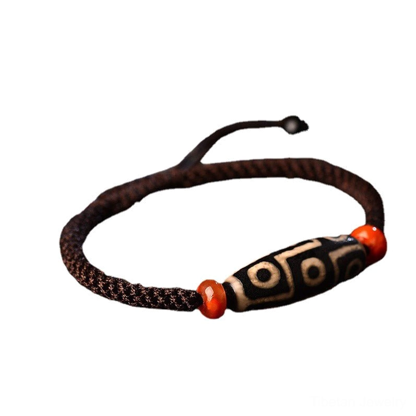 Nine-Eye Dzi bracelet side close-up showing adjustable drawstring cord and detailed bead surface on dark background