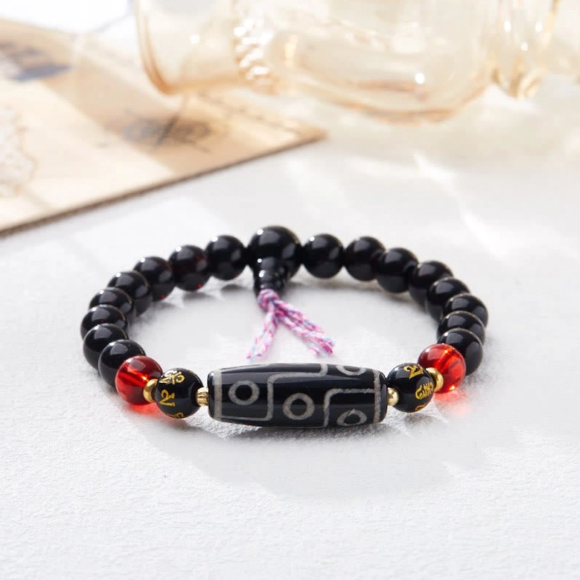 Close-up side view of nine-eye dzi bead bracelet with black onyx and red accent beads