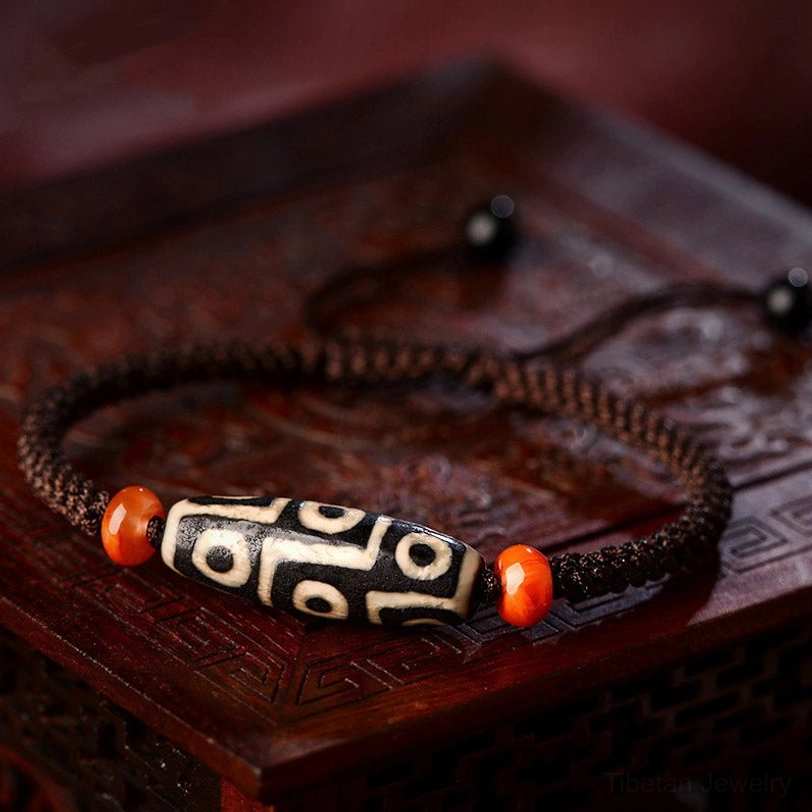 Nine-Eye Dzi bead bracelet close-up on carved wooden box, featuring black-and-white dzi bead and natural agate spacers