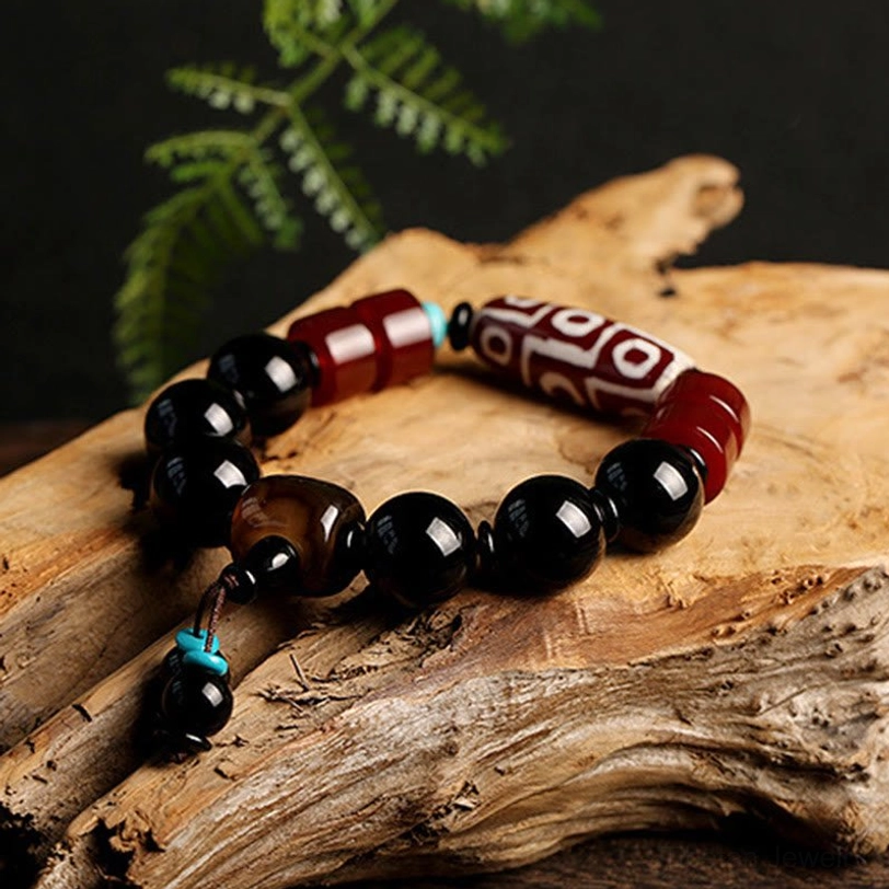 Authentic Tibetan Nine-Eye Dzi Bead Black Onyx Bracelet on natural driftwood with ferns - spiritual wealth protection amulet product photography