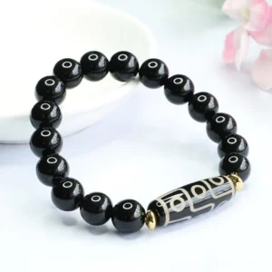 Side view of nine-eye dzi bead protection bracelet showing detailed pattern of dzi bead and glossy black onyx beads arrangement