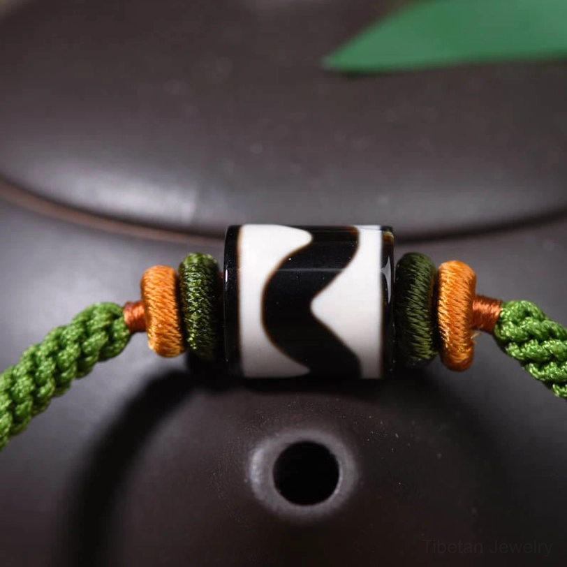 Close-up detail of hand-painted nine-eye dzi bead with tiger stripe pattern and orange spacer beads