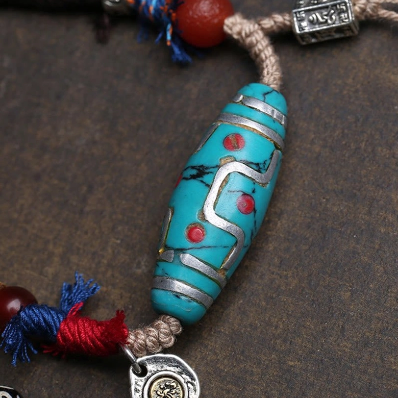Nine-eyed turquoise dzi bead front close-up with silver inlay and embossed ethnic bead pattern