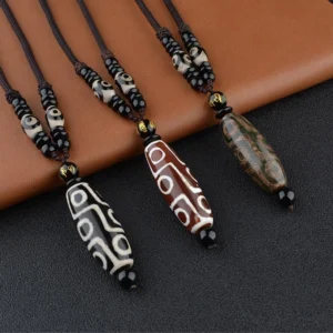 Multiple handcrafted nine-eye Dzi bead necklaces in different colors displayed on brown leather, showcasing traditional Tibetan agate pendant designs