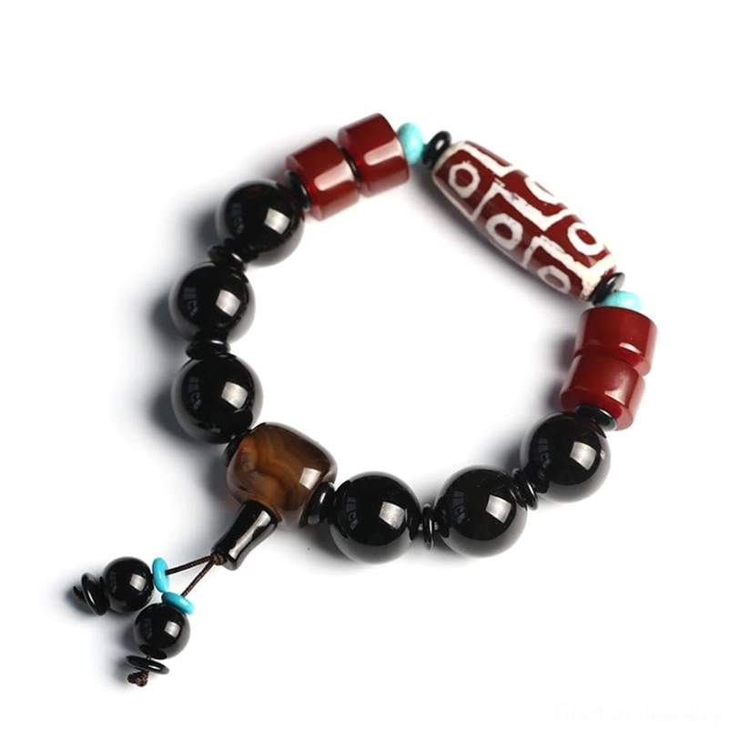 Tibetan Nine-Eye Dzi Bead protection bracelet with Black Onyx beads and turquoise accent on dark background - spiritual jewelry for wealth and prosperity