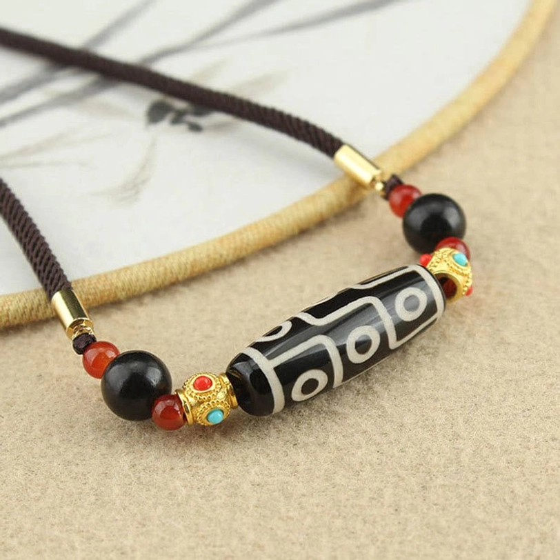 Close-up nine-eye dzi bead pendant with gold metal spacers and red black decorative beads