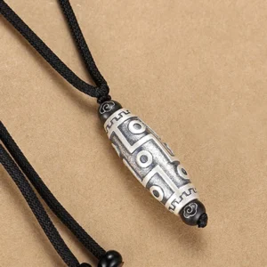 Nine-eye dzi bead pendant side profile showing engraved geometric patterns and detailed craftsmanship