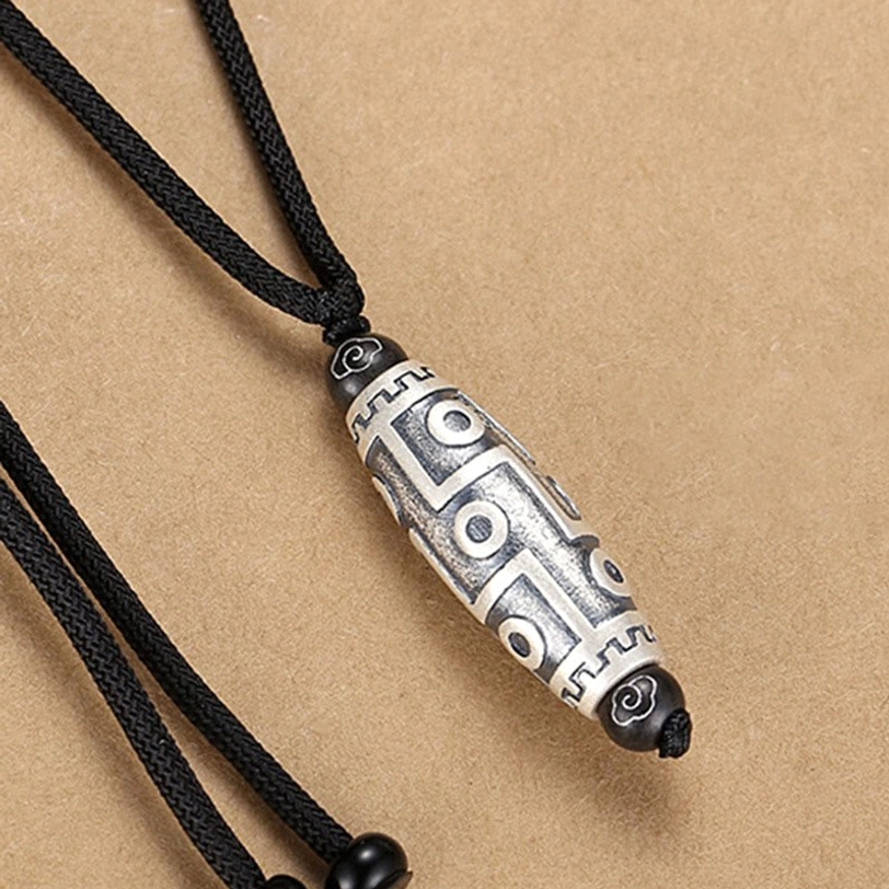 Nine-eye dzi bead pendant side profile showing engraved geometric patterns and detailed craftsmanship