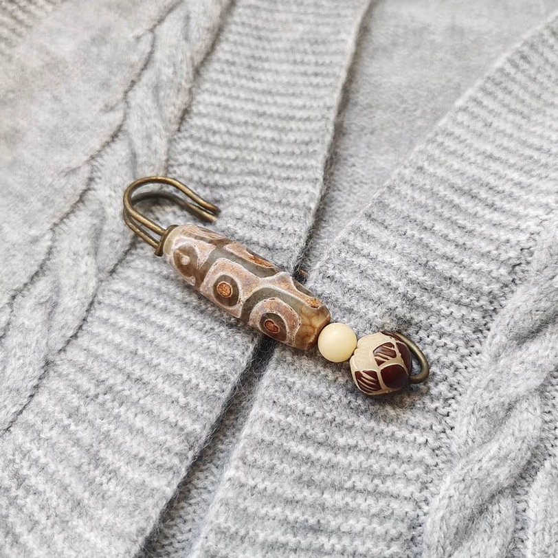 Nine-eye dzi bead brooch pinned to grey knitted sweater, showing how to wear tibetan amulet brooch on knitwear